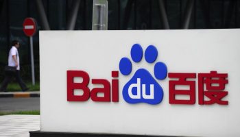 A man walks past the logo of Baidu at it