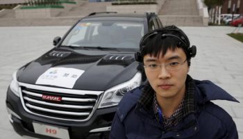 Researcher Zhang Zhao wearing a brain signal-reading equipment poses with a vehicle which can be controlled with his brain wave, during a demonstration at Nankai University in Tianjin