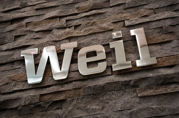 Weill 金屬字體裝飾牆面 Weill 品牌金屬字樣在磚牆裝飾牆面上的特寫,反射光線清晰,氛圍現代感十足.