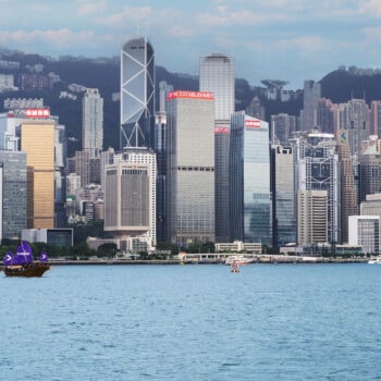 香港天際線與維多利亞港的都市與海景，沿岸高樓大廈耸立，遠景山脈成背景.