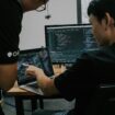 兩位IT專業人員在辦公室討論安全策略,使用電腦和筆記本電腦.