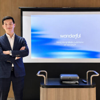 商務專業人士在演講廳前自信站立，背景為投影幕與企業簡報.